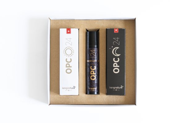 25-08-kn-pr-Produkt-OPC-Geschenkebox-Single-07-AR505207 Eine Pappschachtel, die drei Produkte enthält: zwei rechteckige Schachteln mit der Aufschrift "OPC 24" auf der linken und rechten Seite und eine Flasche in der Mitte mit der Aufschrift "OPC 24 Hand Lotion" von kingnature, alles auf weißem Hintergrund.