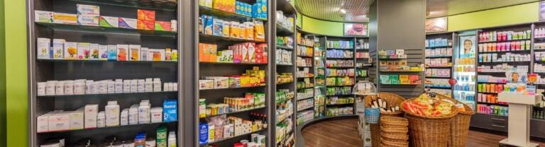 Helles, modernes Interieur der Einsiedler Apotheke mit Regalen voller Nahrungsergänzungsmittel, Körperpflegeprodukte und Drogerieartikel. Weidenkörbe stehen auf dem Boden, und überall im gut organisierten Raum sind farbenfrohe Verpackungen zu sehen.