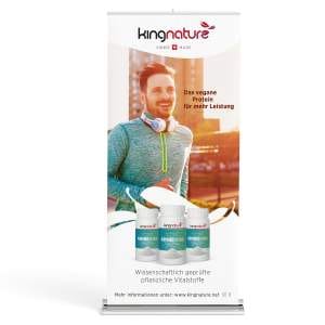 Das Display – Roll-up-Banner zeigt einen lächelnden Mann mit Kopfhörern und drei Kingnature-Supplementflaschen, mit den Texten „Das vegane Protein für mehr Leistung“ und „Wissenschaftlich geprüfte pflanzliche Vitalstoffe“. Das Kingnature-Logo erscheint oben.
