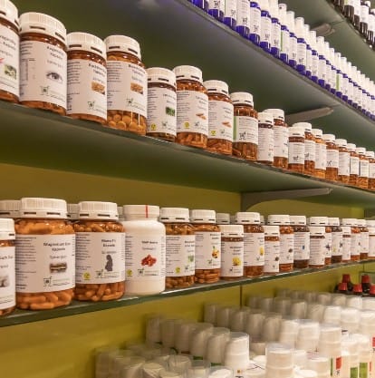 In einer Drogerie in der Spisergasse reihen sich Regale voller Flaschen und Behälter, meist mit weißen Etiketten, ordentlich aufgeräumt aneinander und erinnern an eine übersichtliche Apotheke oder ein Sanitätshaus.